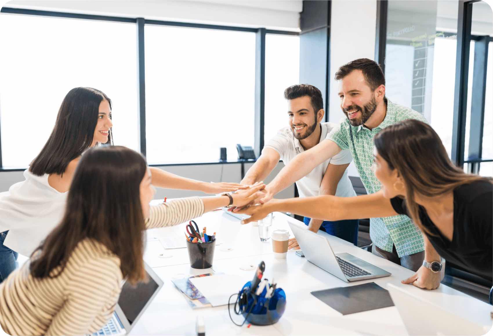 Varios empleados unen sus manos como un equipo en una reunión