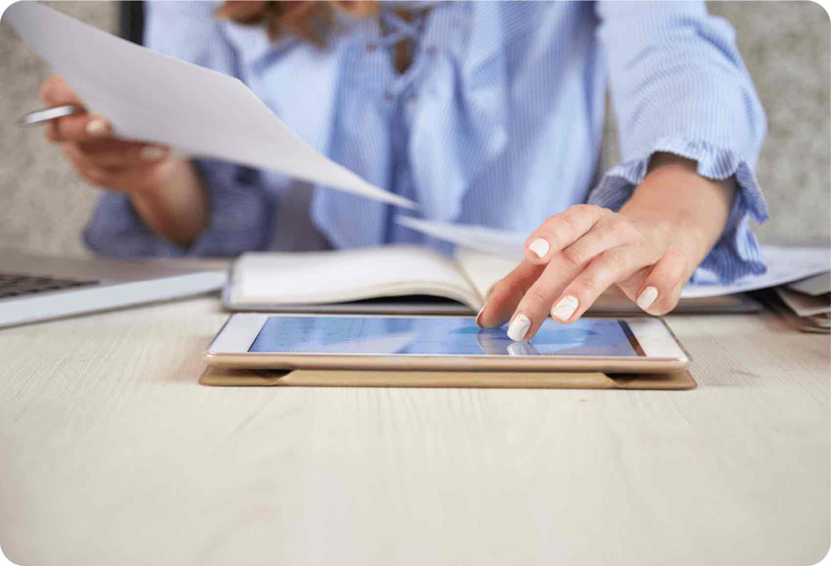 Mujer revisando documentos y con una tablet